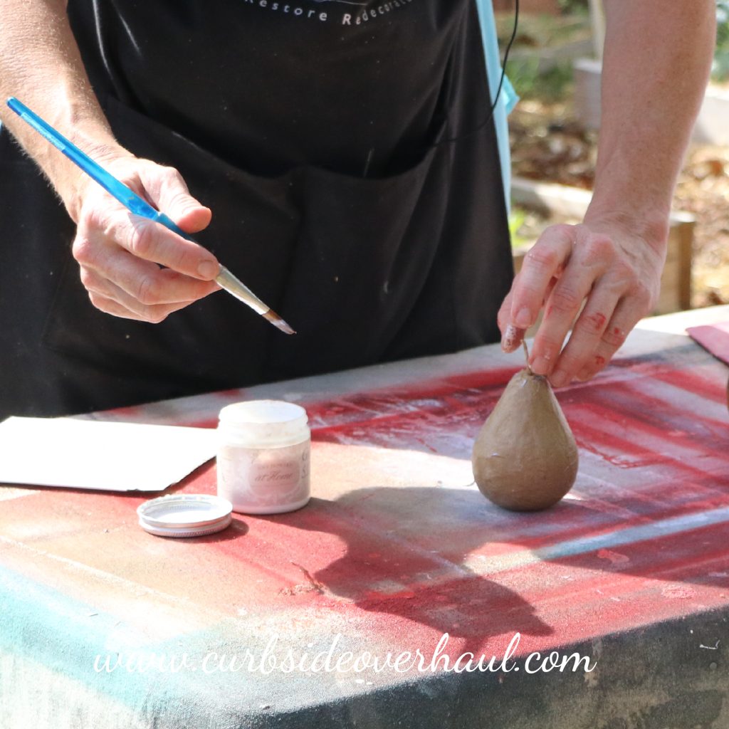 applying guilding size to a paper mache pear