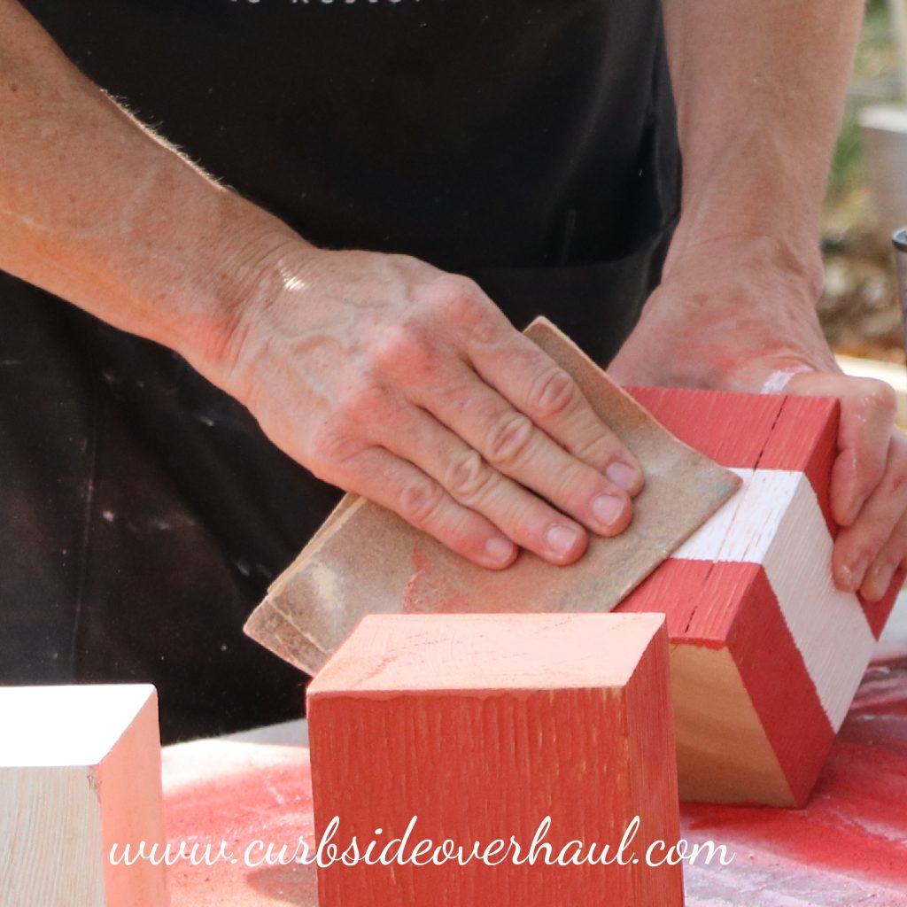 Step Five: Sand  We wanted to keep the rustic and weathered appearance of our wood, so we sanded our secondary color coat to reveal some of the base coat underneath.