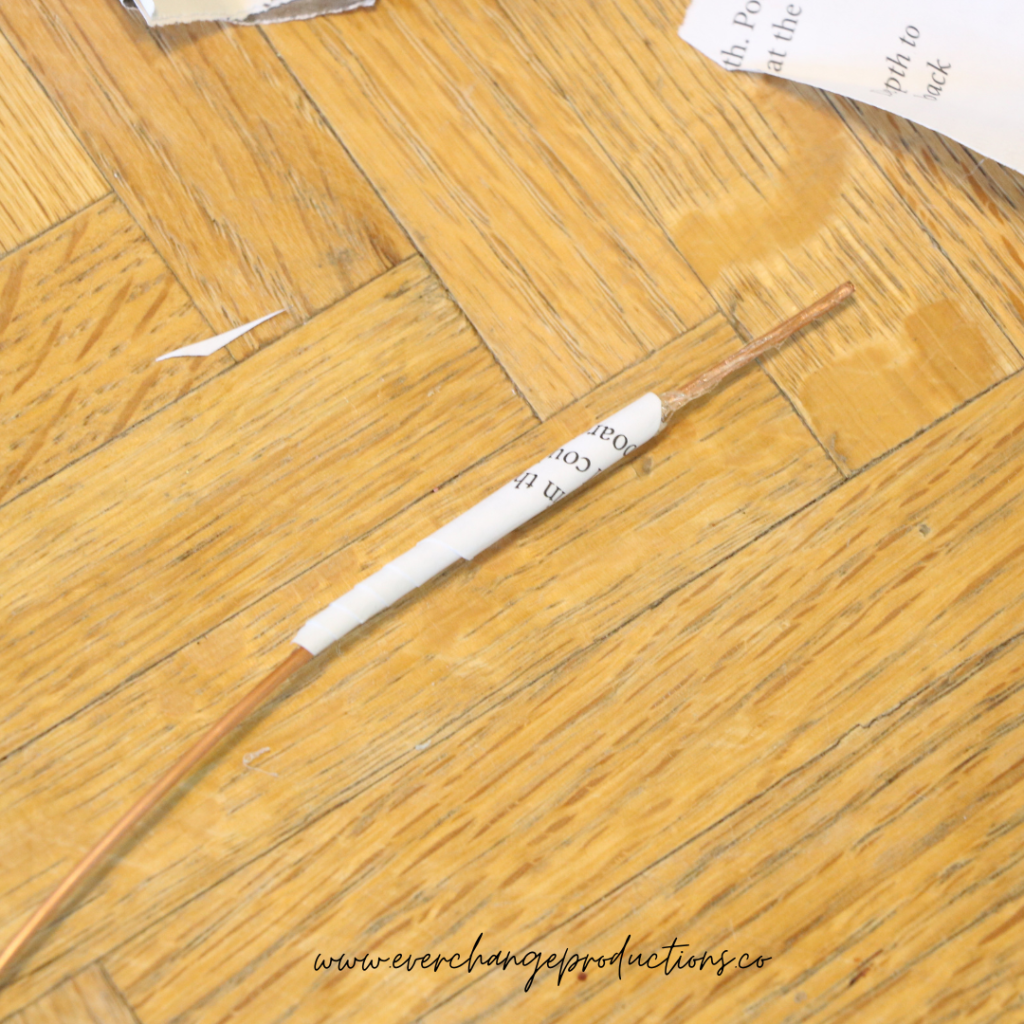 Step 3: Start with the 2 1/2 inch rounded petal. Roll it up into a tube to create its basic shape. Unroll it and run a bead of hot glue along the inside and re-roll it around the end of your wire. Another dot of glue will hold it in place.